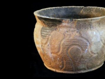 Brown, carved clay pot with flared rim.